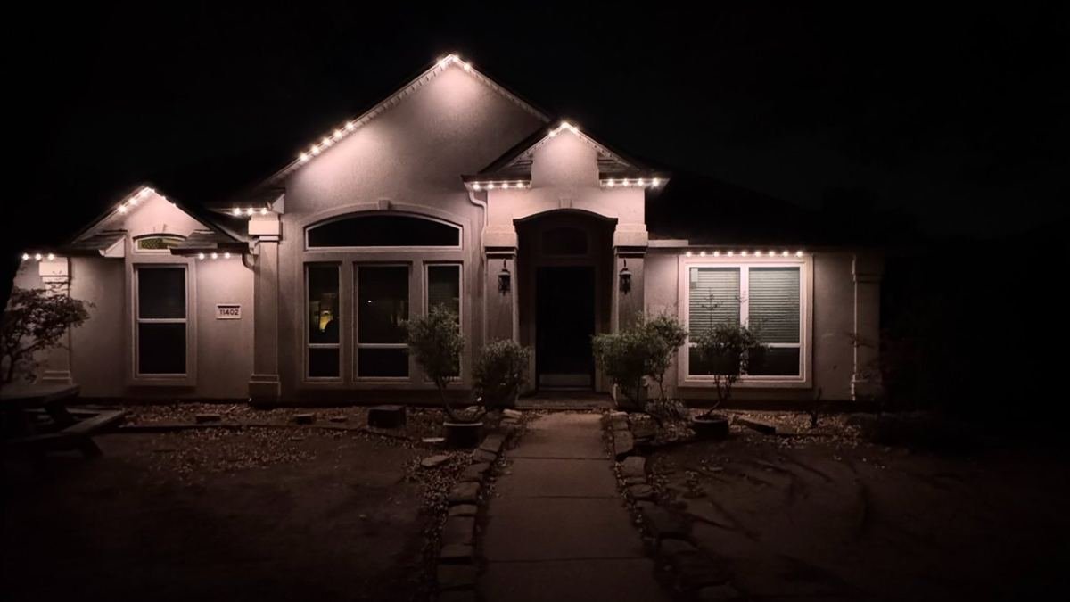 Same home at night after permanent Celebright LED soffit lighting installation — vibrant blue and white lights illuminating the roofline