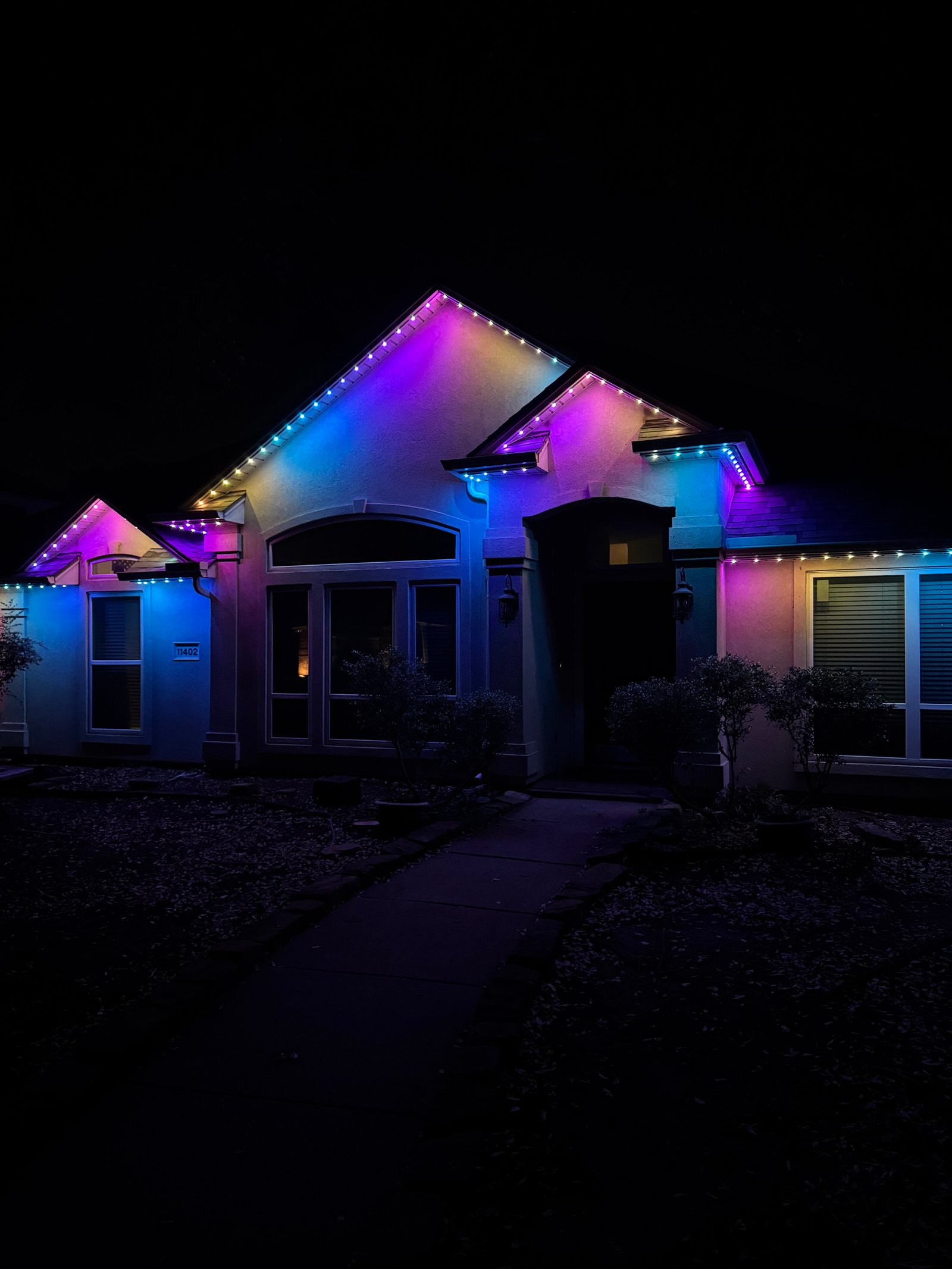 Aerial view of North Texas neighborhood street with multiple homes featuring permanent Celebright LED soffit lighting in various holiday colors